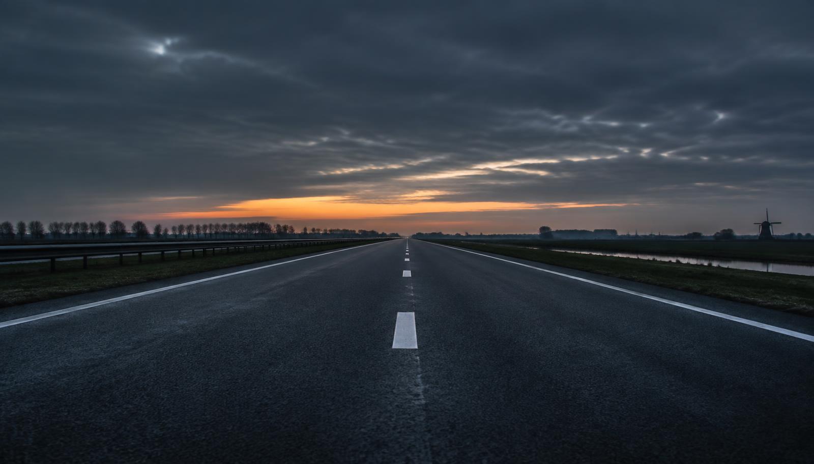 Lege Europese snelweg bij schemer met een oranje gloed aan de horizon